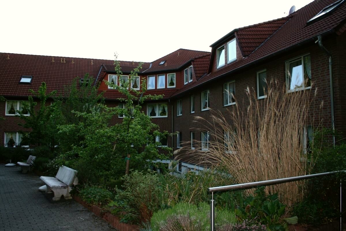 Gartenseite des Hauses mit Gräsern, Sitzbänken und gepflastertem Weg