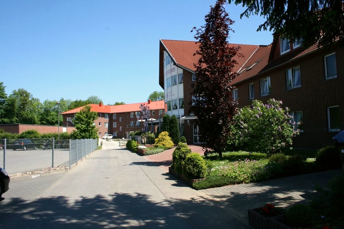 Zufahrt zum Seniorenzentrum mit bepflanzten Beeten und Blick auf das Haus